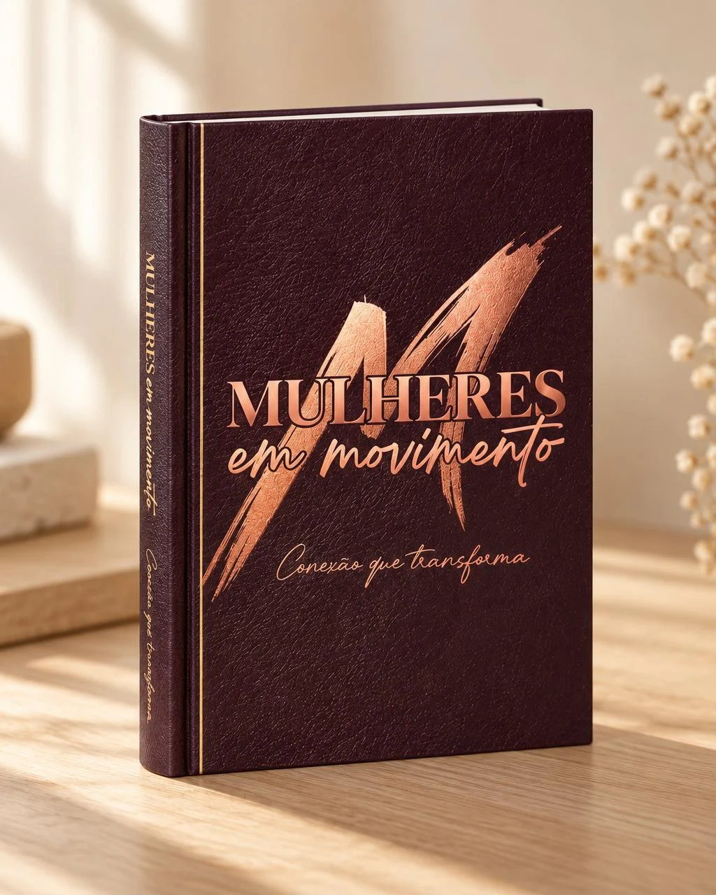 Livro Mulheres em Movimento — Conexão que transforma, de Carol Moura, em pé sobre uma mesa de madeira, com luz natural